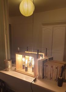 a light on a table with books and a mirror at Studio de la maison Lilas in Pila-Canale