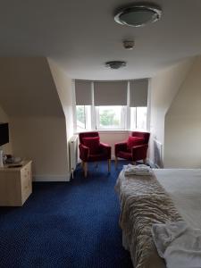 a bedroom with two red chairs and a bed and a window at Aboukir Hotel in Panbride