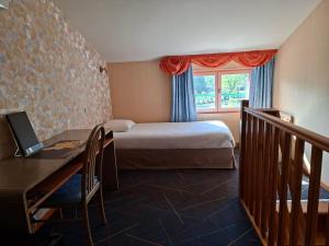 a bedroom with a bed and a desk and a window at Logis Hotel Restaurant Mas de la Prairie in Le Vigan +45 photos