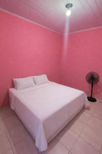 a bedroom with a white bed in a pink wall at Casa completa aconchegante proximo a praia in São Luís