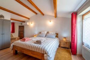 a bedroom with a large bed with red curtains at Maison - Le Petit Bussac in Aigne