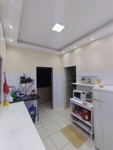 a large kitchen with a counter and a refrigerator at Casa completa aconchegante proximo a praia in São Luís