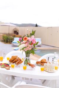 a white table with a vase of flowers and pastries at Villa d'exception - Piscine à débordement - Vue sur la mer - Barbecue - Salle de sport - Jusqu'à 12 personnes in Feddane Chappo