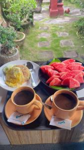 two cups of coffee and a tray of fruit at Tebu menjangan homestay in Banyuwedang