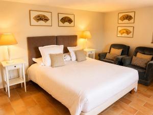 a bedroom with a large white bed and two chairs at La Grange Blanche in Sault-de-Vaucluse