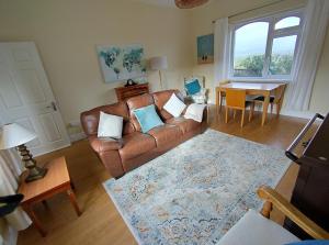 a living room with a leather couch and a table at Kates coastal cottage in Aillemore