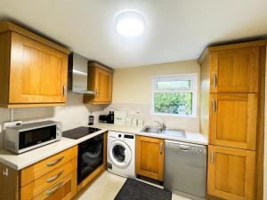 a kitchen with wooden cabinets and a washer and dryer at Kates coastal cottage in Aillemore +15 photos