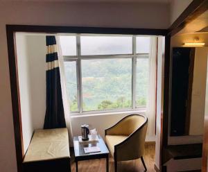 a room with a table and a chair and a window at Hotel Morning Lake in Nainital