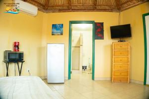 a room with a refrigerator and a tv on the wall at 1-Bedroom Beach Studio - Serene getaways. in San Felipe