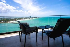 a balcony with chairs and a table and the ocean at Ocean's Embrace and unforgetful sunsets in Progreso