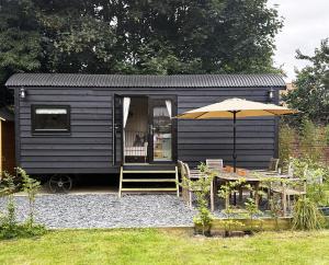 a black tiny house with a table and an umbrella at Orchard House Holiday in Bungay