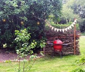 a red grill in a garden with a fence at Orchard House Holiday in Bungay +1 photo