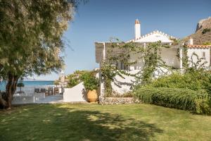 a white house with a grassy yard next to the ocean at Bellevalia Hydra in Hydra