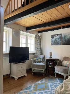 a living room with a flat screen tv and a chair at Historisches Ganghaus "Bluebelle" in Lübeck