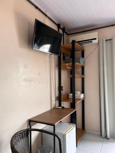 a room with a desk with a television on a wall at Pousada Rota do Parque in Penha