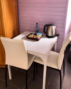 a white table with two chairs and a tea kettle at Le Chant des Elfes in Samer
