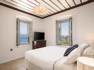 a bedroom with a bed and a tv and windows at Bellevalia Hydra in Hydra