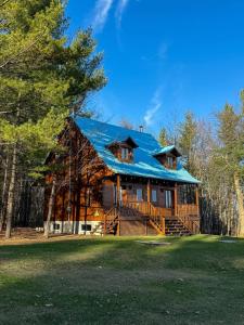 a large log cabin with a blue roof at Les Chalets sur le Cap in Saint-Joachim