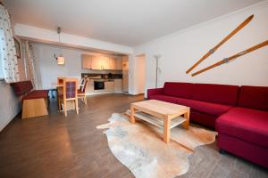 a living room with a red couch and a table at Appartementhaus Kristall incl Joker Card by All in One Apartments in Saalbach-Hinterglemm