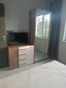 a bedroom with a tv and a dresser with a mirror at ВЕСЕЛА ВАКАНЦИЯ Китен in Kiten