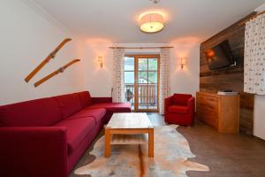 a living room with a red couch and a table at Appartementhaus Kristall incl Joker Card by All in One Apartments in Saalbach-Hinterglemm