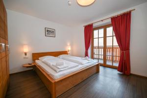 a bedroom with a bed and a large window at Appartementhaus Kristall incl Joker Card by All in One Apartments in Saalbach-Hinterglemm