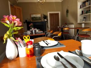 a dining room with a table with a vase of flowers at Lomond Guest House in Leven