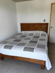 ein Bett in einem Zimmer mit einem hölzernen Bettgestell in der Unterkunft Humedal2 in El Culenar
