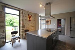 a kitchen with a counter and a large window at Le presbytère de thiat in Thiat