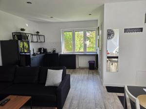 a living room with a black couch and a kitchen at Apartamenty Nowielice in Nowielice