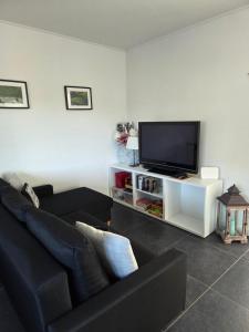 a living room with a black couch and a flat screen tv at Apartamenty Nowielice in Nowielice