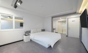 a bedroom with a white bed and a flat screen tv at Busan Gwangalli Nuri Hotel in Busan