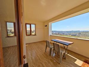 a dining room with a table and chairs and a large window at Garden House Apartments in Kʼanakʼerravan