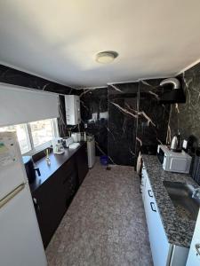 a kitchen with black marble walls and a white refrigerator at Los Altos Pergamino in Pergamino