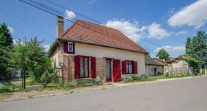a small brick house with red doors on a street at Ô pré de ma fleur in Brévonnes