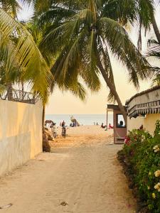 a beach with a palm tree and people on the beach at Villa Keur Lune - Saly - SENEGAL in Saly Portudal