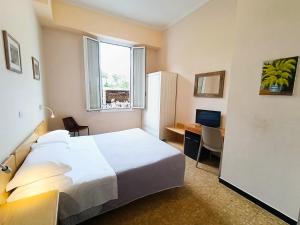 a bedroom with a bed and a desk with a computer at Hotel Villa Bianca in Laigueglia