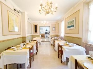 a row of tables in a restaurant with a chandelier at Hotel Villa Bianca in Laigueglia