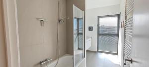 a white bathroom with a shower and a window at Zeebrugge Sea View, Family-Friendly & the Beach! in Zeebrugge