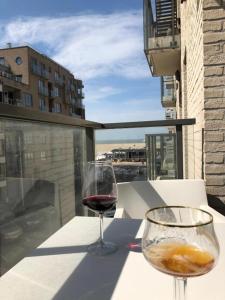 two glasses of wine sitting on a table on a balcony at Zeebrugge Sea View, Family-Friendly & the Beach! in Zeebrugge +43 photos