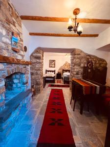 a living room with a stone fireplace and a red carpet at KRIS Guest House in Berat