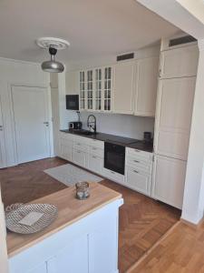 a kitchen with white cabinets and a wooden floor at Charmig bottenvåning i Limhamn in Limhamn