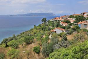 a village on a hill next to the water at Olive Cottage in Skopelos Town