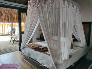 a bedroom with a bed with white curtains at Hotel Budamar Zipolite in Zipolite