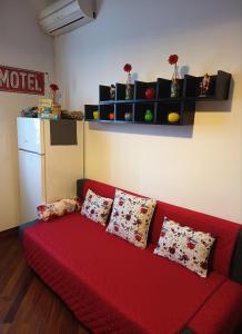 a red couch in a living room with pillows on it at Le Petite Maison in Andria +14 photos