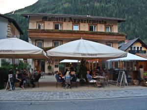 people sitting at tables under umbrellas in front of a building at Hotel Mallnitz in Mallnitz