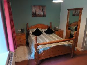 a bedroom with a wooden bed and a large mirror at Beechwood Farmhouse in Yelverton