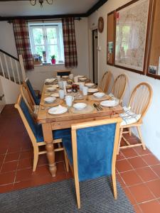 a wooden table with chairs and plates on it at Beechwood Farmhouse in Yelverton
