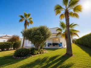 a house with two palm trees in a yard at Villa Savanna Spacious villa with private pool near the beach in Cala en Blanes