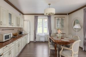 a kitchen with a wooden table and chairs and a table and a dining room at Lillium in Merķeļi